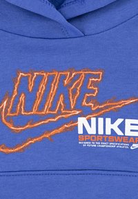 Plavi dukserica s velikim, narančastim izvezenim logotipom "NIKE" i bijelim natpisom "SPORTSWEAR". Ima kapu i teksturirani materijal.
