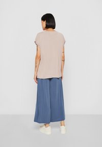 Beige īsām piedurknēm blūze ar brīvu piegriezumu, apvienota ar platām zilām culottes biksēm. Komplektā ir maiga tekstūra un vienkāršs dizains.