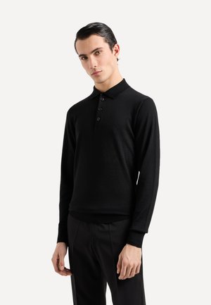 Polo shirt nero a maniche lunghe con colletto, bottoni a tre posti e polsini e orlo a costine. Realizzato in un tessuto morbido e testurizzato.
