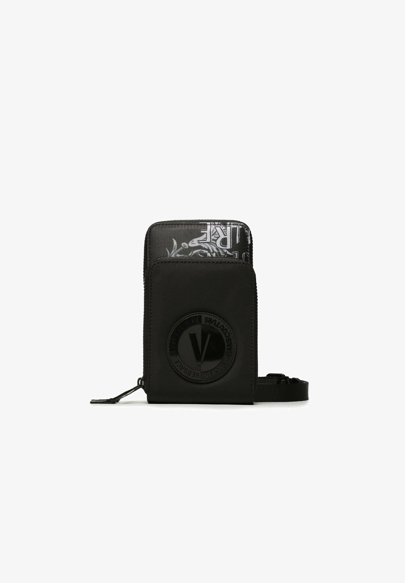 Bolsa compacta negra con bolsillo frontal con cremallera, logo circular en relieve y compartimento interior en blanco y negro parcialmente visible con diseño de texto.