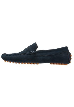 Mocassin homme en daim bleu marine avec surpiqûres mocassin et semelle en caoutchouc avec picots, présenté en profil latéral sur fond blanc.