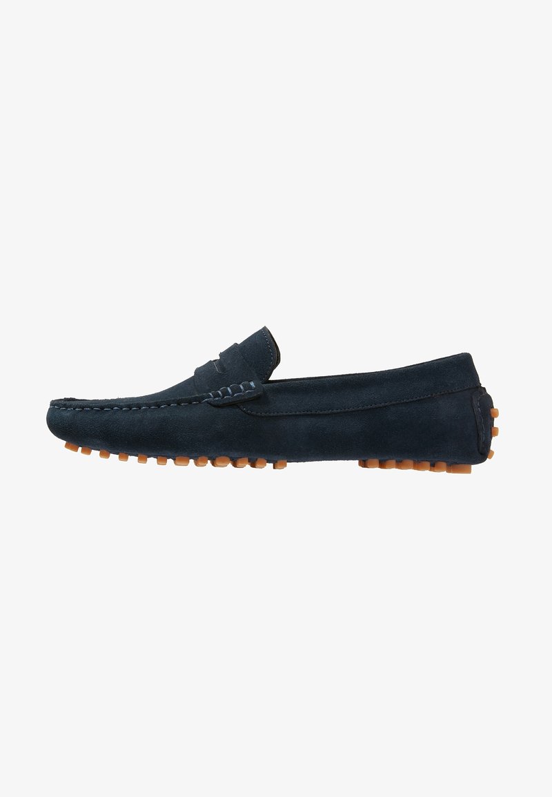 Mocassin homme en daim bleu marine avec surpiqûres mocassin et semelle en caoutchouc avec picots, présenté en profil latéral sur fond blanc.