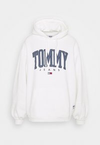 Sudadera blanca con capucha y bolsillo frontal, texto "TOMMY" en azul marino, texto "JEANS" más pequeño, y un pequeño logotipo en rojo, blanco y azul marino debajo del texto.