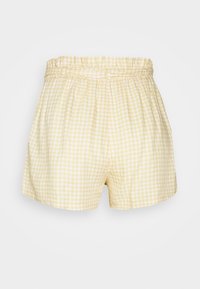 Žluté a bílé šortky pro ženy s károvaným vzorem, s vysokým pasem a detaily na poutkách na opasek na bílém pozadí.