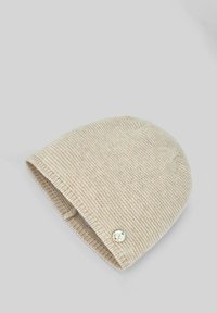 Bonnet en tricot de couleur beige clair, présentant un motif texturé et un petit bouton décoratif sur le côté, avec un bord roulé.