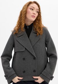 Grijze peacoat van een wolmix met een dubbele rij knopen, ingesneden revers en grote zwarte knopen. Voorzien van wijde mouwen en een losse pasvorm.