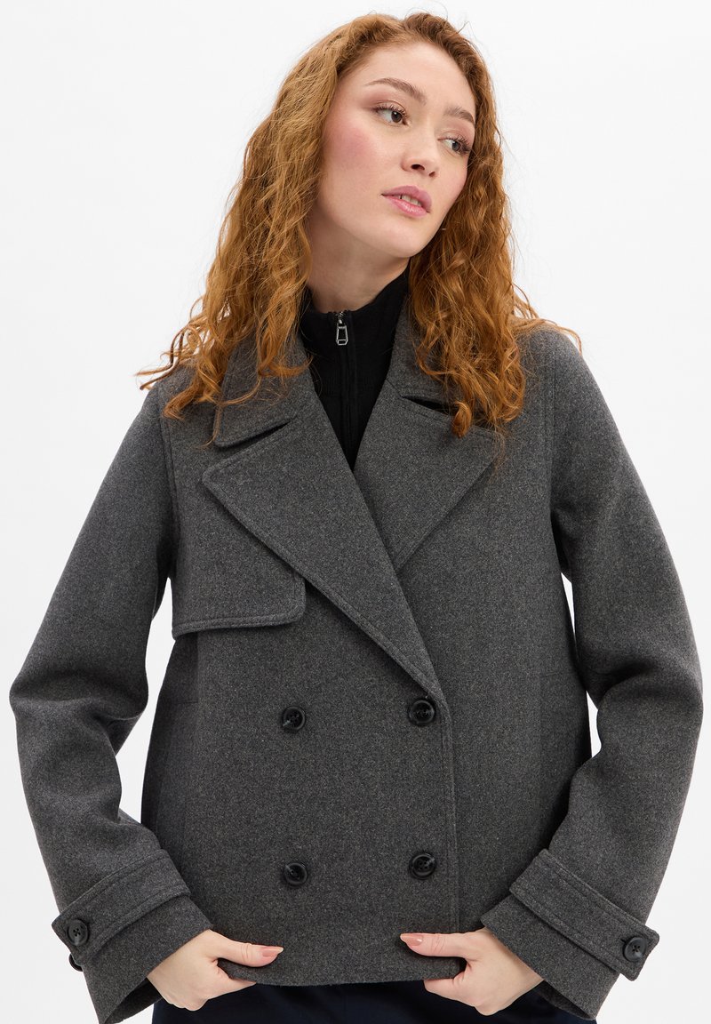 Grijze peacoat van een wolmix met een dubbele rij knopen, ingesneden revers en grote zwarte knopen. Voorzien van wijde mouwen en een losse pasvorm.