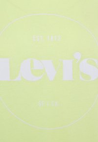 Camiseta verde claro de algodón, con un gran logotipo blanco de "Levi's" y "EST. 1873 SF / CA." impreso en un diseño circular.