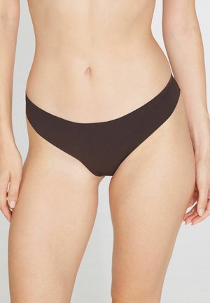 Buste féminin portant un bas de bikini marron foncé uni, montré de la taille jusqu'aux cuisses supérieures sur un fond uni.