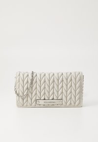 Borsa a tracolla trapuntata di colore grigio chiaro con una tracolla in catena argentata e una placca con logo. Presenta un motivo a zigzag e una forma rettangolare.