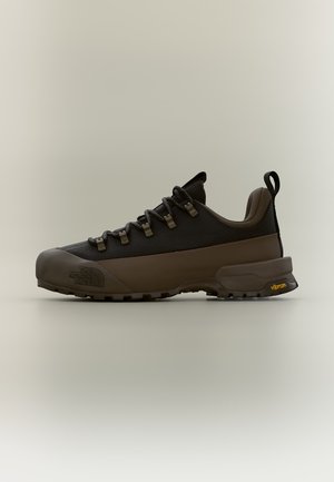 Niskie buty do wędrówek w ciemnobrązowym i czarnym kolorze z podeszwą Vibram i pętelką na pięcie, widok z boku na jednolitym tle.