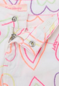 Tessuto di denim bianco con motivi a forma di cuore multicolori in rosa neon, verde, arancione e viola. Presenta una chiusura con cerniera e bottone con etichetta.