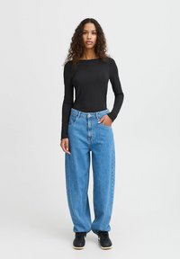 Black ribbed long-sleeve top paired with loose light blue denim jeans. The outfit includes a button and zipper closure, with side pockets.