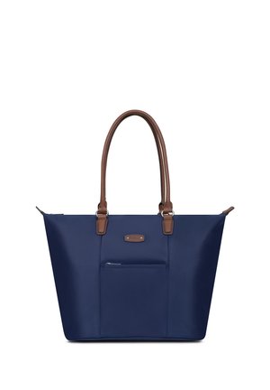 Sac cabas bleu marine avec poignées en cuir marron, poche avant zippée et étiquette de marque rectangulaire sur une surface en tissu lisse.
