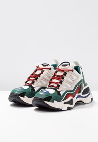 Tjocka sneakers med en blandning av gröna, svarta, röda och blå accenter. Tillverkade av mesh och mocka, med texturerade överdrag och kontrasterande snören.