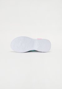 Suela de goma blanca con un patrón texturizado y acentos coloridos en rosa y verde en la parte superior. Presenta un diseño de estrella en la suela.