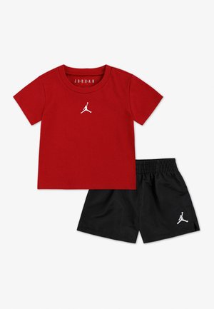 Rood Jordan-T-shirt met korte mouwen en wit Jumpman-logo, gecombineerd met zwarte shorts met een wit Jumpman-logo op het linker been.