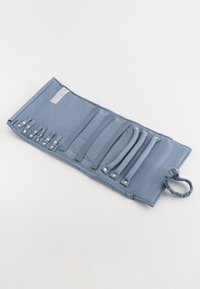 Blå tygförvaringsrulle med flera elastiska remmar och metallknappar för att säkra föremål, avslutad med en rynkad ögla för enkel upphängning.