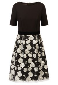 Schwarz eng anliegendes Kleid mit kurzen Ärmeln, ausgestattet mit einem Spitzenrock, der mit weißen Blumenstickereien verziert ist, sowie einem schwarzen Taillenbund.