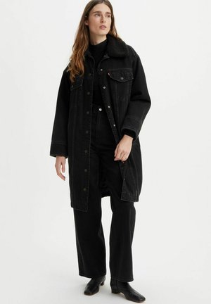 Zwarte denim lange jas met een sherpa kraag, oversized pasvorm, voorzakken en drukknoopsluiting. Gemaakt over een zwart top en wijde broek.