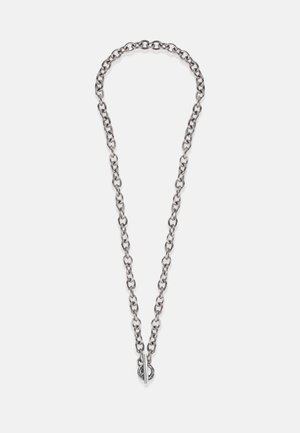 Hõbedane kettkaelakee, millel on ovaalsed lingid, esitleb lülitusklambrit koos ümmarguse aktsendiga. Sile tekstuur ja ühtlane metalliline viimistlus.