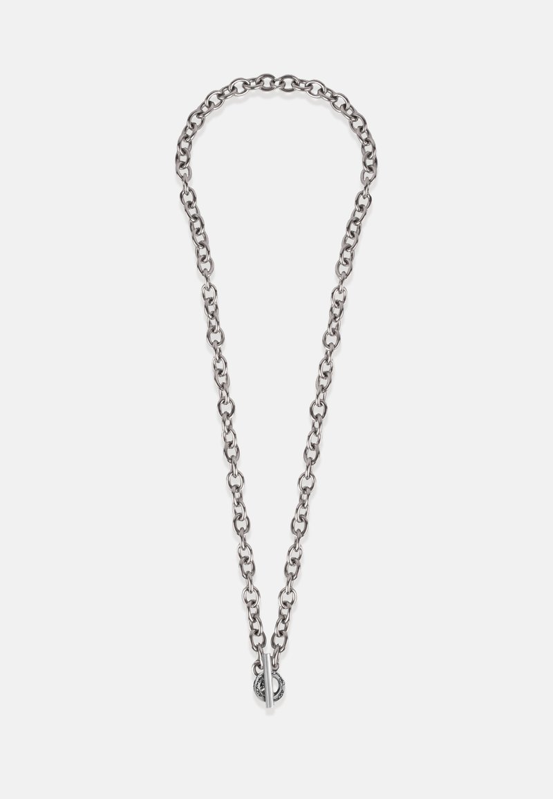 Ez egy ezüst láncnyaklánc ovális szemekkel, amelyen egy kör alakú díszítéssel ellátott záródás található. Simaszövet és egységes fémes felület jellemzi.