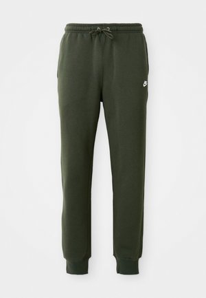 Pantalones de chándal verde oscuro hechos de una tela suave, con cinturilla ajustable y tobillos ajustados. Logo de Nike impreso en el muslo izquierdo.