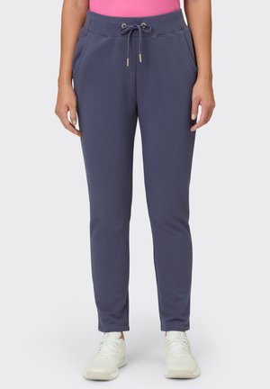 Navy sweatpants with a drawstring waist, two side pockets, and tapered legs. Made of soft, smooth fabric and paired with white sneakers.