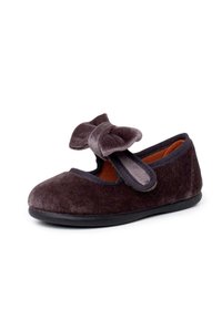 Zapato de terciopelo gris oscuro con punta redondeada, correa en el empeine y un gran lazo decorativo. Presenta una suela de goma negra y un interior suave.