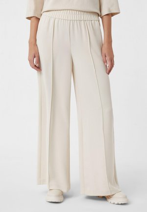 Pantaloni a gamba larga in tessuto beige chiaro, con vita elastica, texture morbida e pieghe frontali per un ulteriore dettaglio di design.