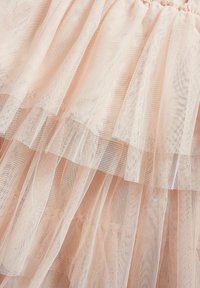 Lagdeltej tulle i blød pink, med bølgede kanter og en let, luftig tekstur. Designet viser subtil transparens og bevægelse.