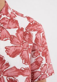 Witte korte mouwen shirt van linnen, met een grote rode bloemenprint en een klassieke kraagontwerp.