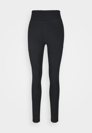 Črne legice iz raztegljivega materiala, z visokim pasom, rebrastimi paneli ob straneh in prilegajočim dizajnom, ki se zoži pri gležnjih.