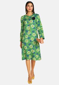 Grünes Blumenkleid mit großen weißen Rosen und blauen Akzenten, langen Ärmeln, knielangem Schnitt, glatter Textur und A-Linien-Silhouette.