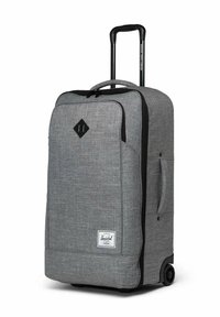 Valise en tissu gris avec poignée télescopique, poignée de transport latérale, poche zippée à l'avant et roues noires.
