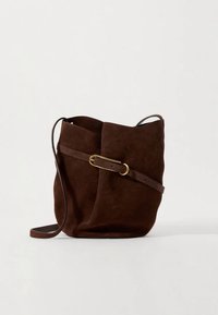 Sac seau en daim marron avec une seule bandoulière en cuir et une boucle ceinture en métal doré. Texture douce, design simple.