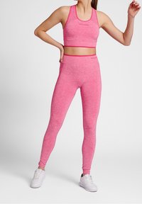 Růžový sportovní crop top a legíny z texturované látky. Set má přiléhavý střih s detaily z síťoviny a plochými švy.