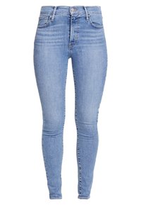 Jeans skinny in denim blu con una texture liscia, vita alta e design a cinque tasche, caratterizzati da una leggera scoloritura e dettagli di cucitura.