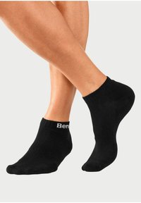 Schwarze Knöchelsocken mit geripptem Muster und einem weißen "Ben"-Logo am Bündchen. Einfaches Design, weiches Material und enganliegende Form.