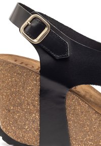 Sandal in pelle nera con suola in sughero a zeppa. Caratterizzato da una cintura con una fibbia dorata rettangolare e finitura in pelle liscia.