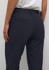 Marinblå skräddarsydda byxor med en mjuk tygkvalitet, slim fit, och två bakfickor med stängda sömmar. Bältesöglor och en ren midjeresdesign.