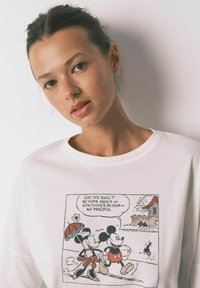 Felpa bianca con una stampa in bianco e nero di Mickey e Minnie Mouse che camminano. Il design include fumetti e dettagli.