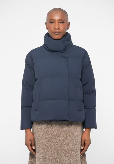 Veste matelassée bleu marine avec col haut, design matelassé et poches latérales. Elle offre une coupe décontractée et un rembourrage épais pour l'isolation.