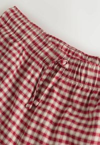 Červené a béžové kárované bavlnené šortky majú elastický pás so šnúrkou. Tkanina má jemnú textúru a vzor kociek.