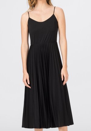 Černé midi šaty s tenkými ramínky na špagetách, plisovanou sukní a hladkou látkou, s přiléhavým živůtkem a volným střihem od pasu dolů.