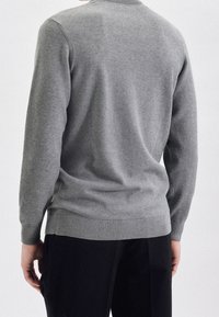 Pull gris en maille avec un col rond et des poignets et une base côtelés, présentant un motif texturé et une coupe décontractée.