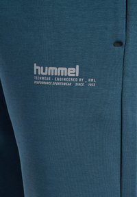 Blauwe sportkleding met een zachte textuur, Hummel branding en opvallende stiksels. Ontworpen voor prestaties en comfort.