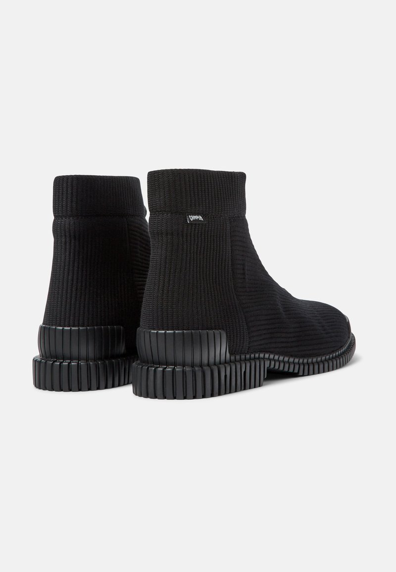 Schwarze Knöchelboots mit einem gerippten Strickoberteil und einer strukturierten Gummisohle mit horizontalen Rillen. Minimalistisches Design und keine sichtbaren Beschläge.