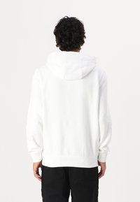 Witte katoenen hoodie met een ruime capuchon, ribgebreide manchetten en zoom, en een gladde textuur. Het ontwerp is eenvoudig en onversierd.