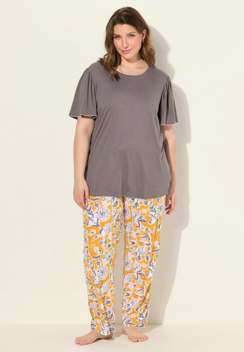 Top gris de manga corta con mangas abullonadas, combinado con pantalones de pijama amarillos con un patrón floral que presenta detalles en blanco y gris.